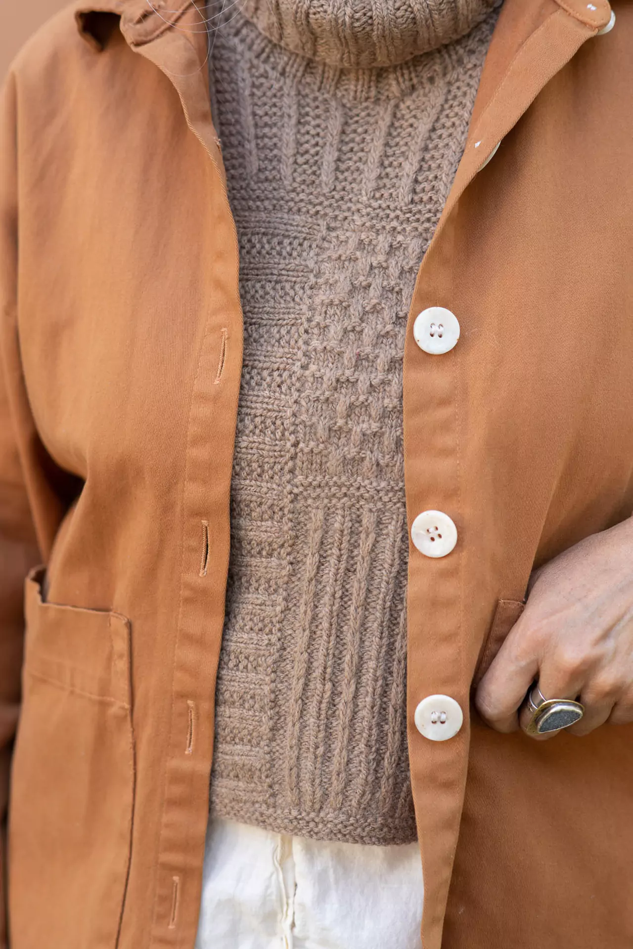 A close up image of a woman's torso with a textured handknitted dickey accessory worn beneath a jacket