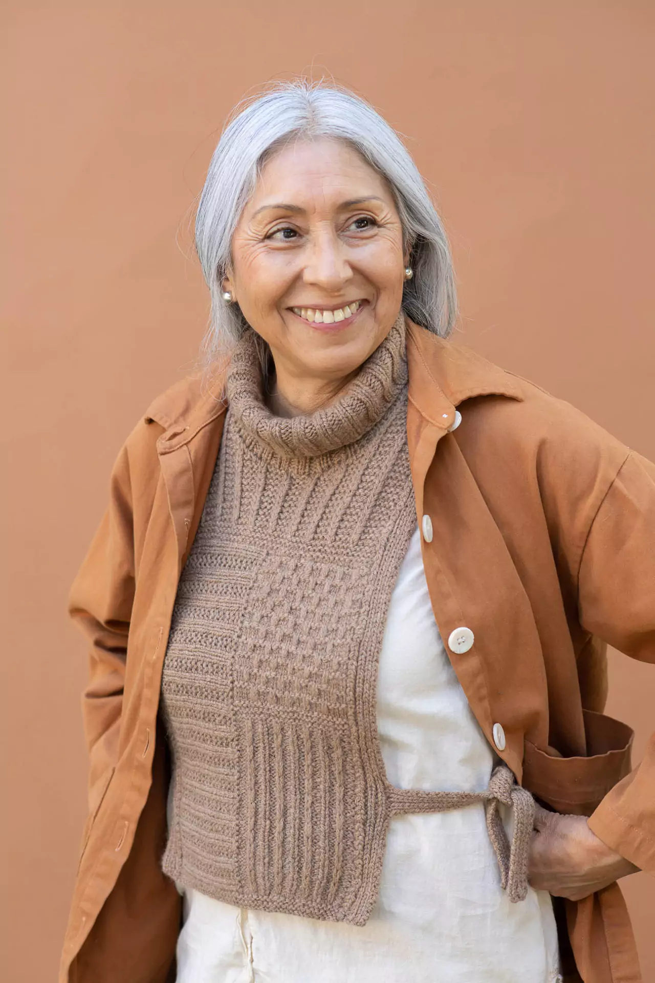 A mature silver-haired woman wearing a textured hand knitted dickey beneath a jacket