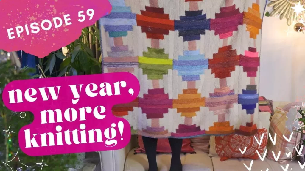 Thumbnail for The Crimson Stitchery knitting video showing a woman standing on a sofa holding up a large, colourful handknitted blanket, and text reading New Year More Knitting